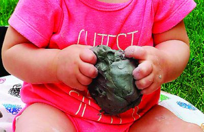 An infant at Rodef Shalom ECC explores the properties of clay.