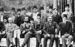 Yechezkel Sasson, seated center, in fez, sits directly to the left of the dark-bearded King Faisal I of Iraq in Baghdad in a photo from the 1920s. (Wikimedia Commons)