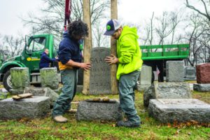 Workers place headstones back on their bases on Feb. 21 morning at Chesed Shel Emeth Cemetery in the St. Louis area. (James Griesedieck/St. Louis Jewish Light)