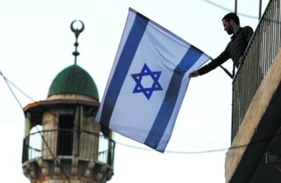 A young Jewish man raises an Israeli flag in the Arab Quarter of the Old City, 2009. (Abir Sultan/Flash90)