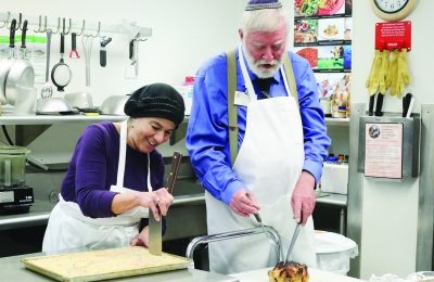 Terry, l, and Ira Indich preparing Shabbat dinner in the Shalom Park kitchen.