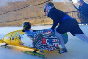 Dave Nicholls, seated, rides in the bobsled.