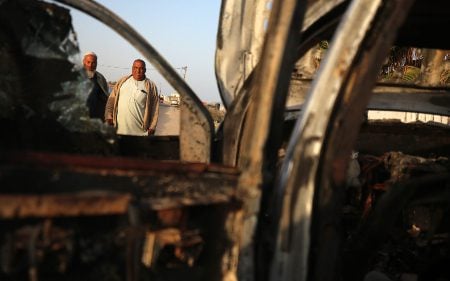 Palestinians stand next to a vehicle, where volunteers from the World Central Kitchen, including foreigners, were killed in an Israeli airstrike, according to the NGO, in Deir Al-Balah, in the central Gaza Strip, April 2, 2024. (Majdi Fathi/NurPhoto/Getty)