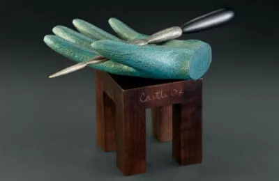 Torah pointer (yad) by Wendell Castle. Silver and stained walnut; hand: sign foam and acrylic paint; table: rosewood, maple wood. 8 in. high. (2004). Barr Foundation collection. (Fralin Museum of Art at the University of Virginia)