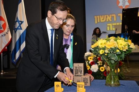 Israel President Isaac Herzog lights the first Chanukah candle together with injured veteran and IDF soldiers at Beit HaLochem in Tel Aviv, Dec. 25, 2024. (Amos Ben-Gershom/GPO)