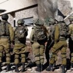 Israeli army forces stand outside a house that was hit by rockets fired by Hezbollah from Lebanon in the northern Israeli border town of Kiryat Shmona on Nov. 26, 2024. (Jalaa Marey/AFP via Getty Images)