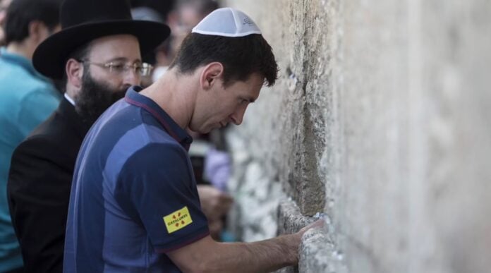 Messi_Kotel Lionel Messi, then with FC Barcelona, puts a note in the Western Wall, during a team trip to Israel and the West Bank, Aug. 4, 2013. (Oliver Weiken/AFP via Getty Images)
