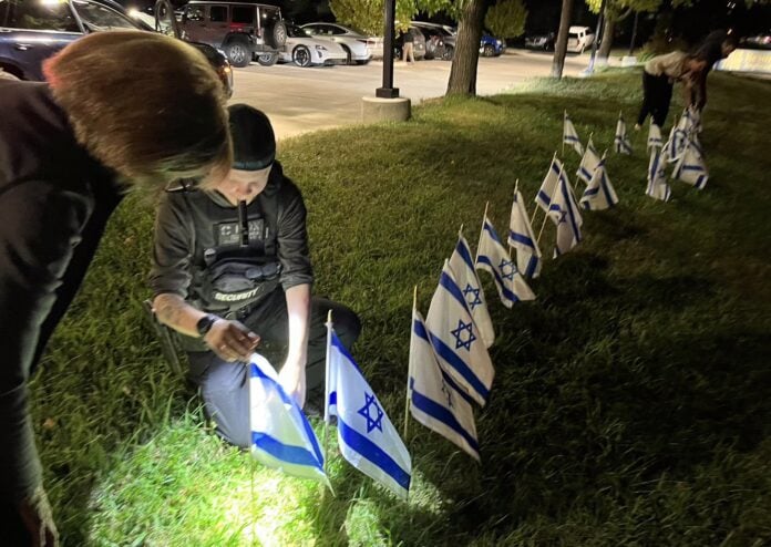 Resurrection_Anglican Temple Emanuel member Noreen Davis looks on as a security professional places an Israeli flag in the front lawn of the Anglican Resurrection Church on Belleview Ave. (Steve Mark)
